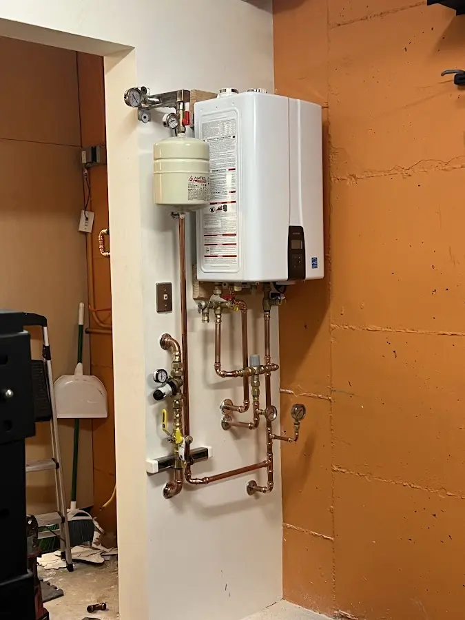 Plumbing technician inspecting water heater connections in Brooklyn Center